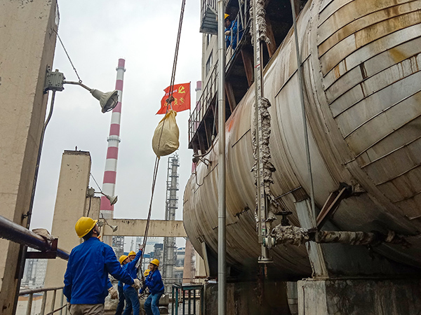 5月10日中午，在動力車間三期工藝除氧器地面，黨員突擊隊隊員用滑輪往工藝除氧器平臺運送鋼絲網(wǎng)，用以纏繞新填料.jpg