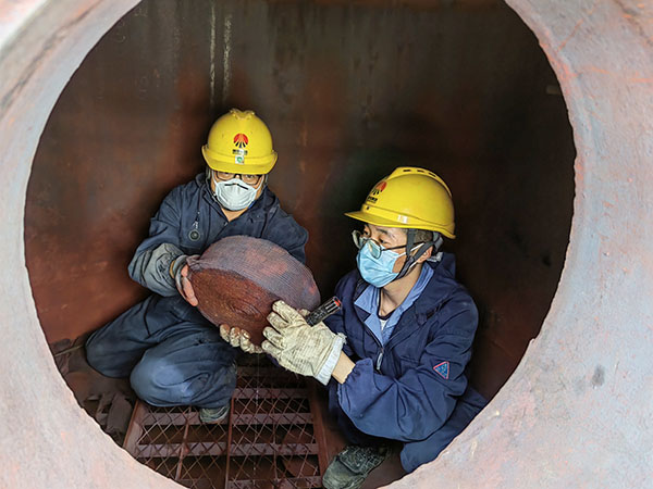 5月11日，動力車間三期工藝除氧器內部，黨員突擊隊隊員劉瑞斌和李震正在清理舊填料.jpg